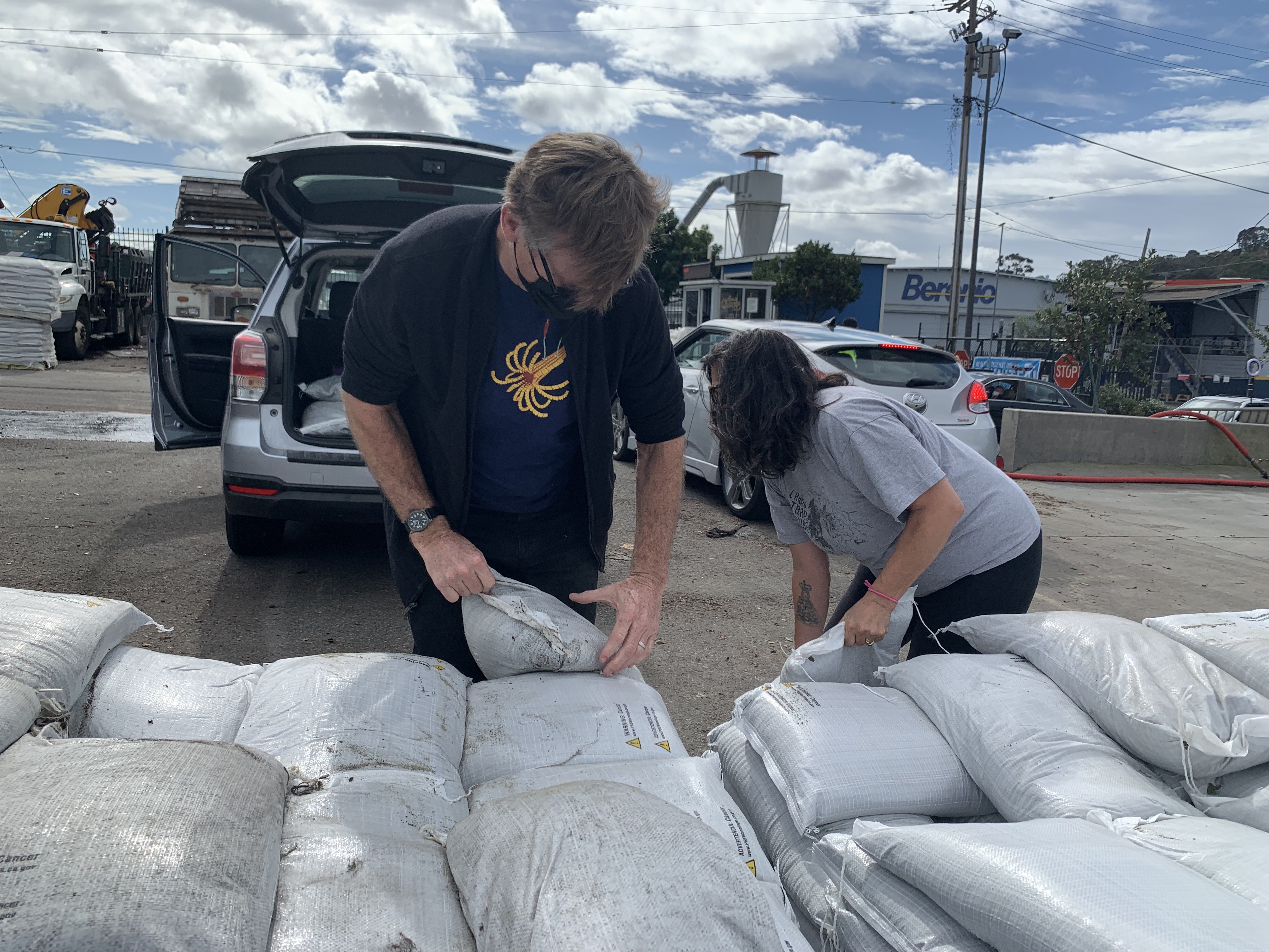 people loading sandbags in their car
